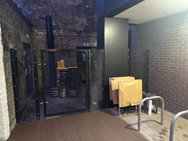 Modern brick sauna entrance with glass door, wooden deck, towel rack with yellow towels, and bicycle rack